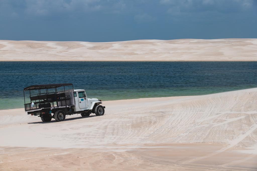 Veículo off-road nas dunas brancas dos Lençóis Maranhenses com lagoa azul