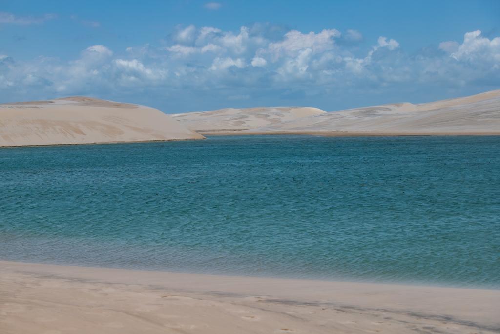 Lagoa azul turquesa com dunas brancas ao fundo nos Lençóis Maranhenses